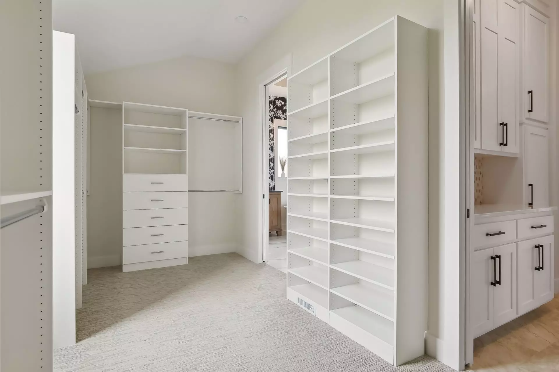 Primary suite walk-in closet with organizers and access to laundry room