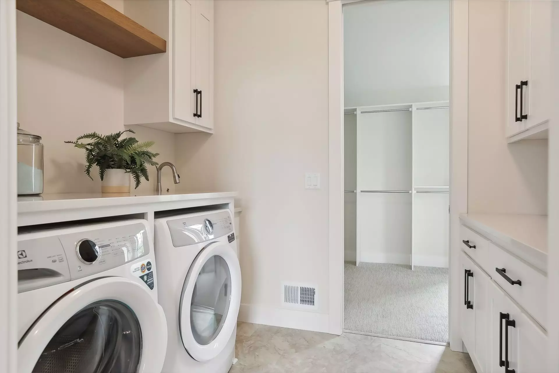 Laundry room with under counter washer dryer and direct access to owner’s suite closet